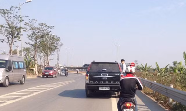 Nam thanh niên đu bám bên hông chiếc xe hạng sang. Ảnh cắt từ clip.