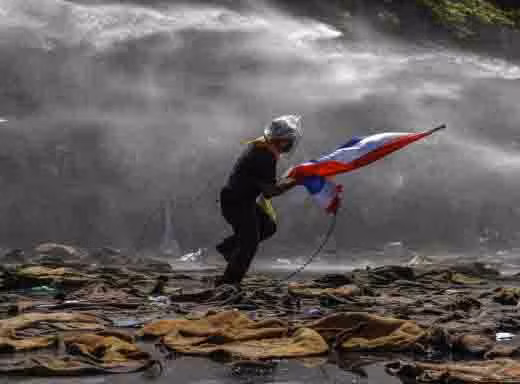 Một người bỏ chạy khi cảnh sát dùng vòi rồng trấn áp biểu tình