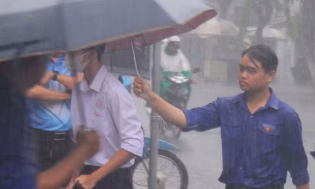 Tình nguyện viên dầm mưa hỗ trợ thí sinh 