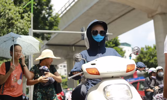 Người dân chống nắng bằng trang phục kín khi đi trên đường Xuân Thủy, Cầu Giấy, Hà Nội chiều 15/7 Ảnh: như ý