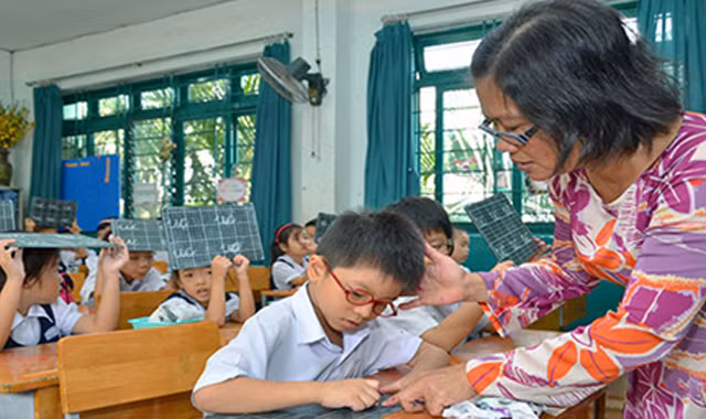 Cô giáo uốn nắn cho học trò từng nét chữ, nết người. Ảnh: Tấn Thạnh/Người Lao Động.