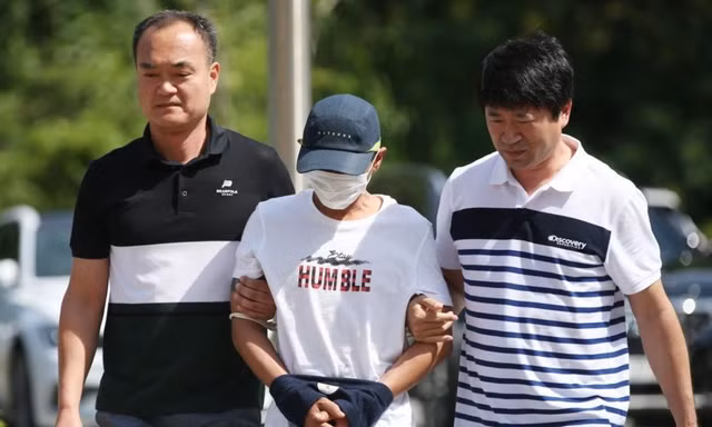 Người đàn ông Hàn Quốc bị tình nghi bạo hành người vợ Việt Nam bị cảnh sát dẫn đi. (Ảnh: Yonhap)