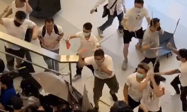 Nhóm côn đồ mặc áo trắng dùng gậy sắt tấn công người dân Hong Kong tại một ga tàu điện ngầm vào cuối tuần trước. (Ảnh: SCMP)