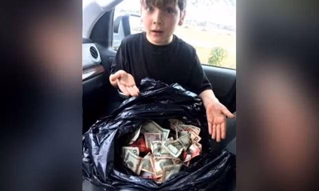 Cậu bé Griffin Steele, 7 tuổi, bên bao tiền lớn cậu tìm thấy gần thùng rác của trạm xăng.