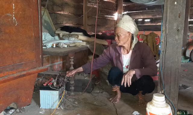 Bà Chìu Thị Tài bên chiếc bình ắc quy cũ kỹ