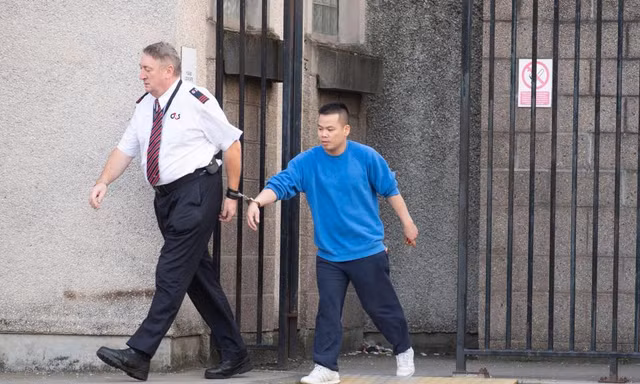 đối tượng Lê Trung Dũng đang bị cảnh sát áp tải (Ảnh: The Scottish Sun)