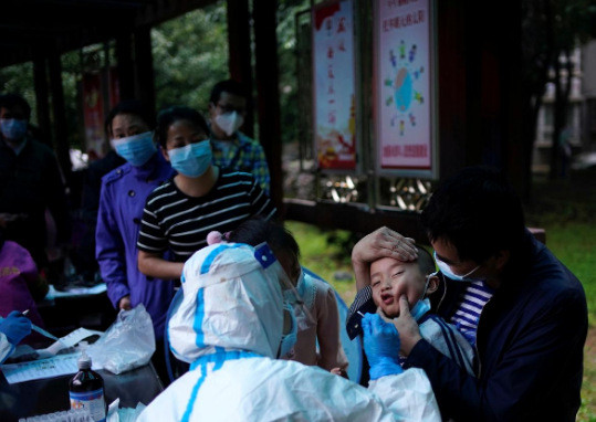 Một em nhỏ được lấy mẫu xét nghiệm ở Vũ Hán. Ảnh: Reuters