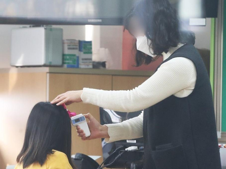 Nữ sinh Hàn Quốc được cô giáo kiểm tra thân nhiệt. Ảnh: Yonhap