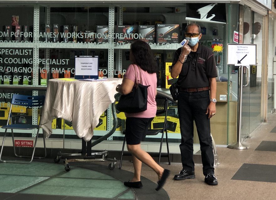 Nhân viên bảo vệ trung tâm thương mại Excelsior đeo khẩu trang, găng tay kiểm tra thân nhiệt mọi khách ra vào và hướng dẫn họ rửa tay bằng dung dịch sát khuẩn, đăng ký thông tin tại quầy trước cổng vào. Ảnh: Thái An.