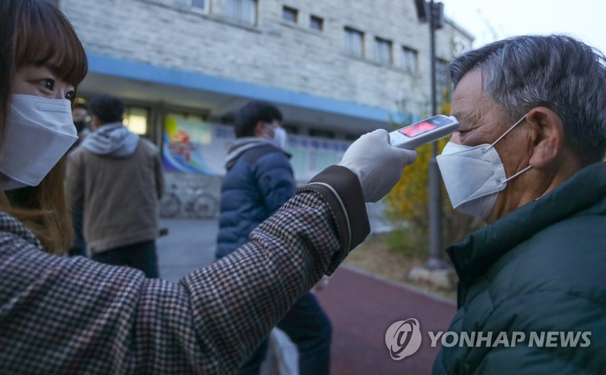 Người dân được đo thân nhiệt ở lối vào trạm bỏ phiếu. Ảnh: Yonhap