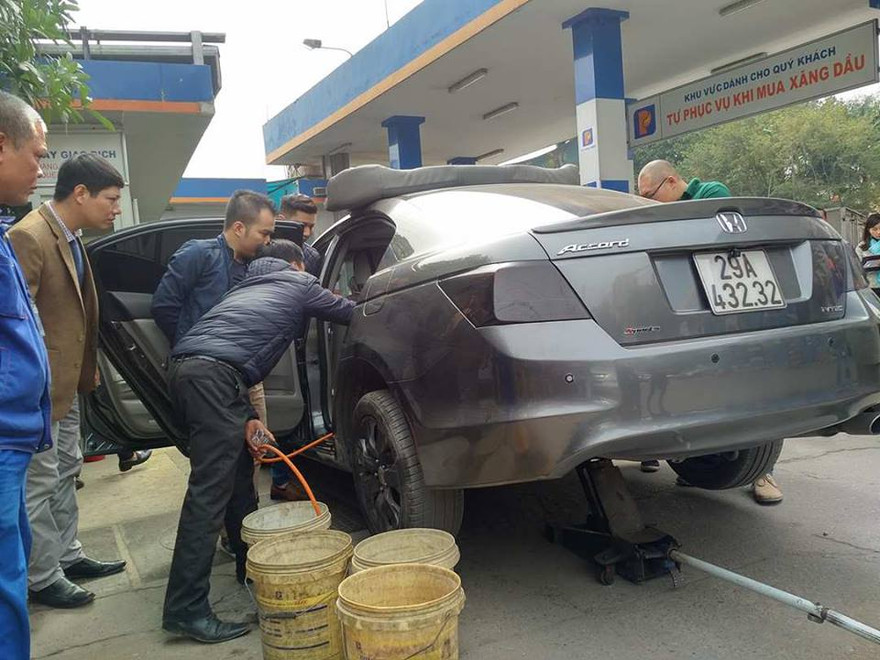 Nhân viên cây xăng rút xăng từ chiếc xe Honda Accord ra thùng. Ảnh: M.Đ