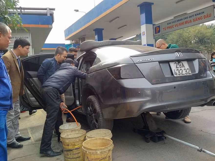 Nhân viên cây xăng rút xăng từ chiếc xe Honda Accord ra thùng. Ảnh: M.Đ