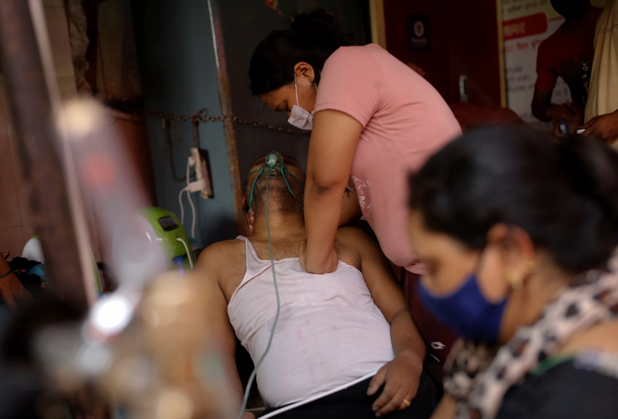 Một phụ nữ Ấn Độ sơ cứu cho người cha mắc COVID-19 sau khi ông này ngất xỉu. Ảnh: Reuters