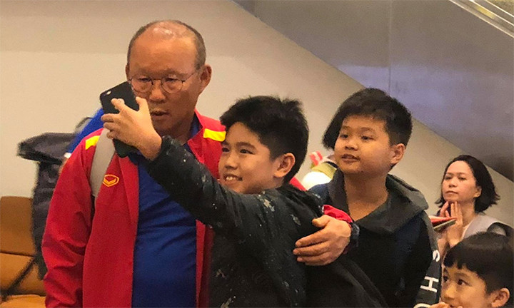 Nhà cầm quân người Hàn Quốc chụp ảnh và ký tặng người hâm mộ trong lúc chờ lấy hành lý. 