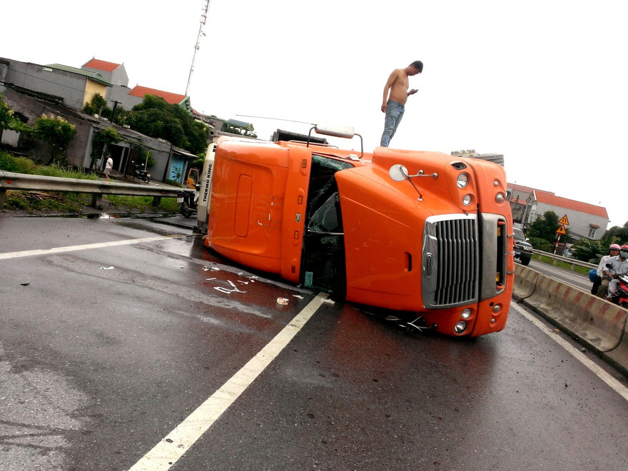 Container chồm lên dải phân cách rồi lật ra đường