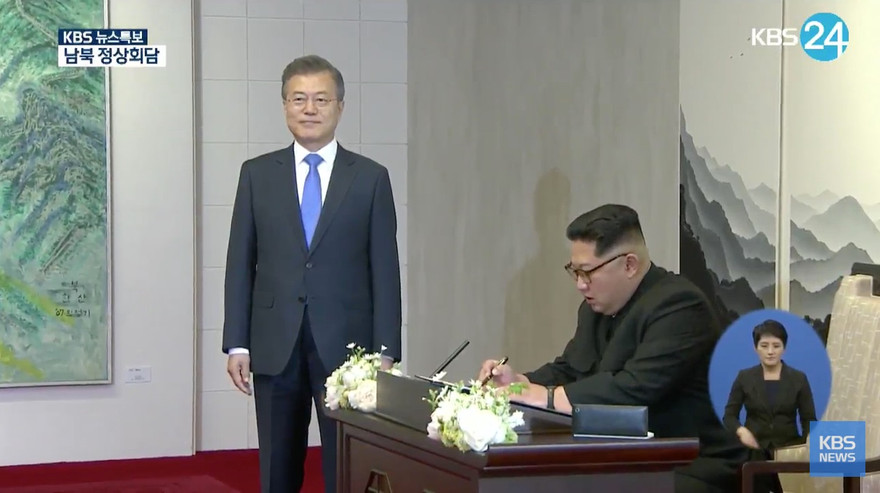 Ông Kim Jong-un ngồi viết lưu bút sáng 27/4 tại Nhà Hòa Bình. Ảnh: KBS