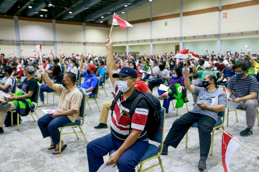 Người dân Indonesia cầm quốc kì khi đi tiêm vắc xin ở Jakarta. Ảnh: Reuters