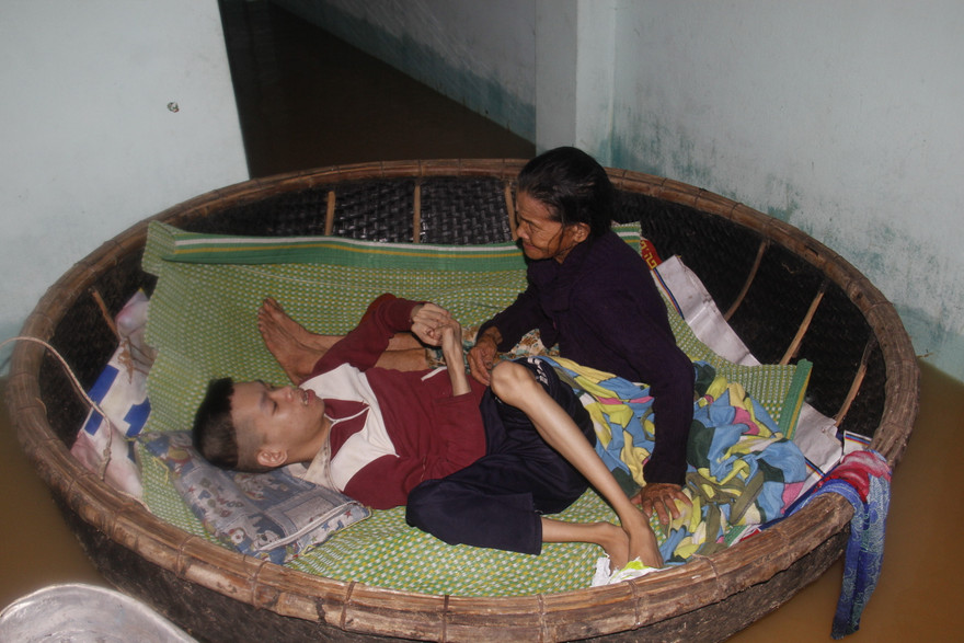 Hai mẹ con bà Đắt trong chiếc thuyền thúng nổi trôi theo nước lũ. Ảnh: Thanh Trần. 
