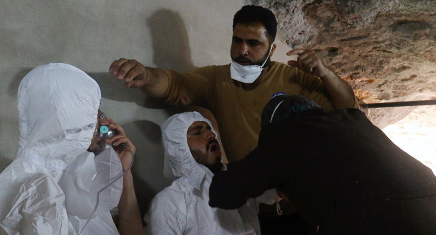 Hai người đàn ông được chăm sóc y tế, thở bằng mặt nạ oxy tại hiện trường vụ tấn công bằng vũ khí hóa học ở Idlib hôm 4/4. Ảnh: Reuters