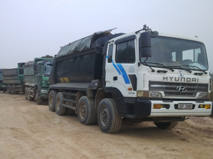 Hàng chục xe tải nối đuôi chở đất đi bán.