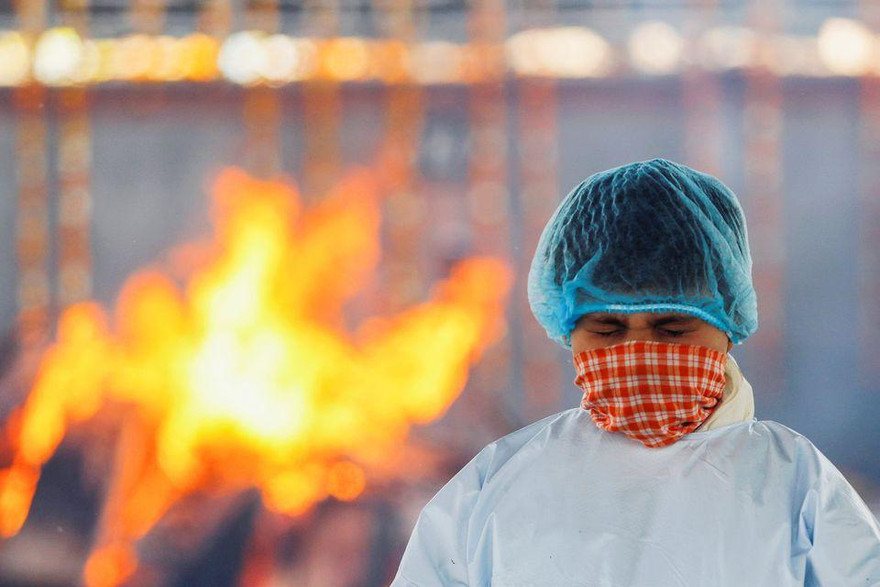 Một bé trai nhắm nghiền mắt khi người cha mắc COVID-19 được hỏa táng ở New Delhi (Ấn Độ). Ảnh: Reuters