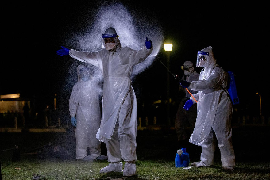 Nhân viên phục vụ tang lễ được khử trùng trong quá trình chôn cất bệnh nhân COVID-19. Ảnh: Straitstimes