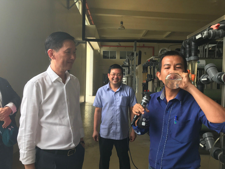 Nhân viên VWS báo cáo quy trình xử lý nước thải từ rác. Đồng thời uống nước thải sau khi đã xử lý trước đoàn công tác. Ảnh Việt Văn