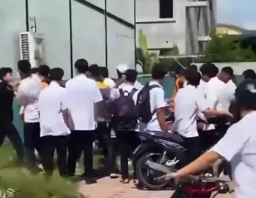 Eine Gruppe von Schülern in weißen Hemden griff einen Klassenkameraden vor dem Schultor an. Foto aus Clip ausgeschnitten. 58.jpg