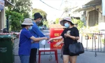 Tình nguyện viên ở chốt phong tỏa “mềm” đường An Dương Vương (quận Ngũ Hành Sơn) hỗ trợ người dân ra vào khu cách ly. - Ảnh: Giang Thanh