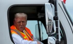 Ông Trump ngồi trên chiếc xe chở rác màu trắng in tên ông. (Ảnh: AP)