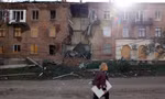 Một phụ nữ đi qua toà nhà bị trúng tên lửa ở Bakhmut, Ukraine. (Ảnh: Reuters)