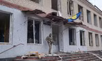 Một lính Ukraine đứng canh trước toà nhà bị hư hại ở làng Barvinkove, tỉnh Kharkiv, ngày 12/4. (Ảnh: Reuters)