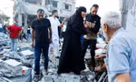 Người dân ở Dải Gaza đứng trên đống đổ nát sau cuộc tấn công của Israel ngày 12/10. (Ảnh: Reuters)