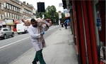 Một người đàn ông vác con lợn vào cửa hàng bán thịt ở London. (Ảnh: Reuters)