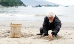 Cụ Mạo đang nhặt rác trên bãi biển Nam Ô. Ảnh: Tấn Lực