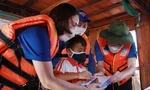 Bí thư T.Ư Đoàn Nguyễn Tường Lâm (ngoài cùng, bên phải) trao tặng máy tính bảng cho em Nguyễn Đức Anh, học sinh lớp 2, trường Tiểu học Văn Đức, sống tại làng chài sông Hồng. Ảnh: Bảo Anh
