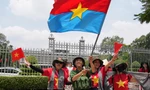 Người dân vẫy cờ Mặt trận Dân tộc Giải phóng miền Nam khi chụp ảnh trước Dinh Độc Lập ngày 29/4. (Ảnh: AP)