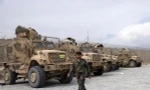 Một binh sĩ quân đội Afghanistan đi ngang qua các phương tiện chống mìn MRAP, bị bỏ lại sau khi quân đội Mỹ rời căn cứ không quân Bagram, ở tỉnh Parwan, phía bắc Kabul, Afghanistan, ngày 5 tháng 7 năm 2021. Quân Mỹ rời Sân bay Bagram của Afghanistan sau gần gần 20 năm đồn trú.