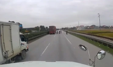 Các thanh niên đi xe máy không đội mũ đánh võng trước mặt container