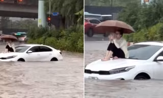 Danh tính cô gái leo lên nóc capo, ung dung ngồi giữa 'biển nước' ở Hà Nội sáng nay