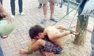 Hình ảnh thiếu niên 16 tuổi bị trói vào gốc cây