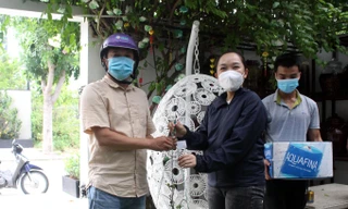 Chậu lan rừng phi điệp được Thảo (áo đen) bán cho khách hàng với giá... 2 thùng nước lọc. Toàn bộ số nhu yếu phẩm này sẽ được hỗ trợ cho các chốt kiểm dịch và khu phong tỏa. Ảnh: Giang Thanh