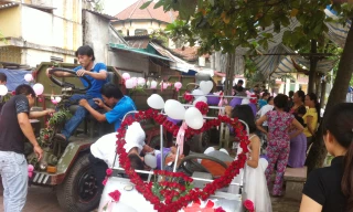 Chiếc xe điện màu trắng chú rể tự lái chở cô dâu và năm chiếc xe công nông chở hàng trăm khách