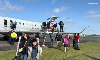 Hành khách mở cửa thoát hiểm, chen chúc trèo lên cánh máy bay 