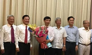 Phó Chủ tịch UBND TPHCM Võ Văn Hoan (thứ ba từ phải qua) trao quyết định và tặng hoa chúc mừng ông Nguyễn Văn Tám