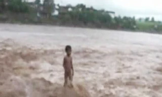 Cậu bé bốn tuổi đứng giữa dòng nước lũ