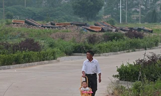 Một ông bố đưa con đi dạo qua đoạn đường có rất nhiều quan tài mới bị đập vỡ ở tỉnh An Huy.