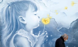 Một cụ ông đeo khẩu trang đi qua bức tranh tường ở nhà ga Athens (Hy Lạp) ngày 15/11. Ảnh: AP 