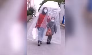 Hai mẹ con đeo khẩu trang và trùm túi nhựa kín mít chống virus corona