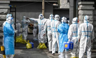 Nhân viên y tế xếp hàng chờ được khử trùng. Ảnh minh họa: AP